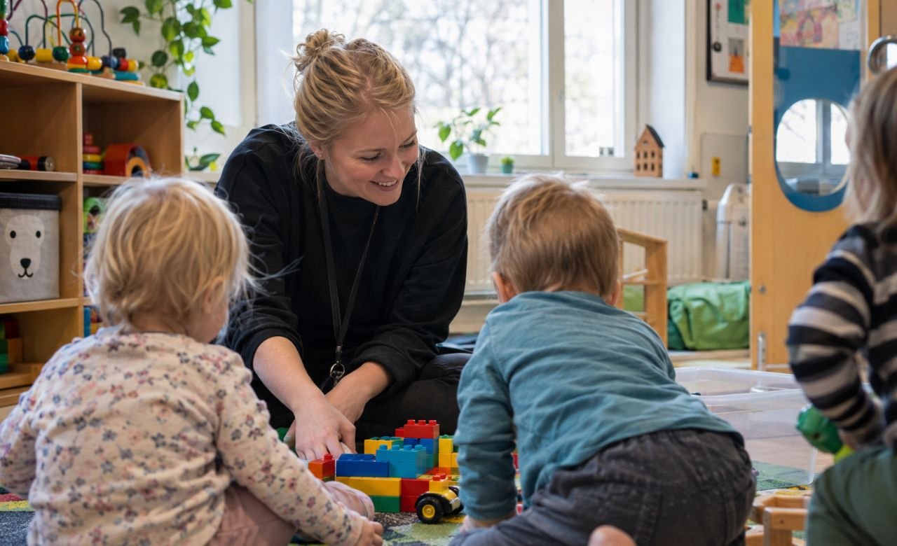 kuva lastenhoitajasta leikkimässä lasten kanssa päiväkodissa